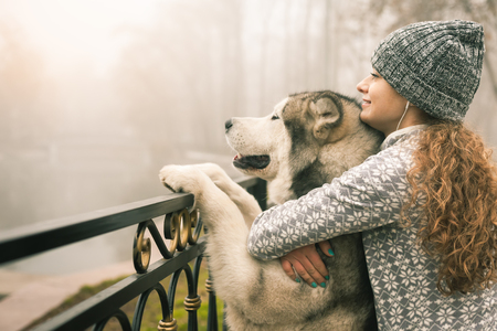 Image of young girl with her dog, alaskan malamute, outdoor at autumn or winter. Domestic pet. Huskyの写真素材