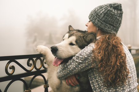 Image of young girl with her dog, alaskan malamute, outdoor at autumn or winter. Domestic pet. Huskyの写真素材