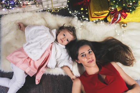 Cute baby and happy mum near Christmas tree. New Year 2017. Fairy tale. Mothercare is most important in children life. Baby and daughterの写真素材