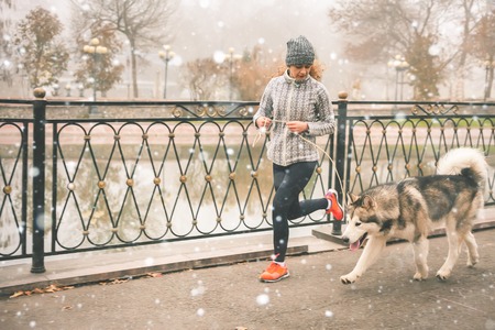 Image of young girl running with her dog, alaskan malamute, outdoor at autumn or winter. Mourning...