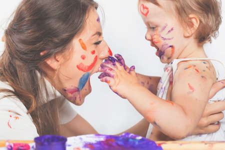 Happy mom and baby playing with painted face by paintの写真素材