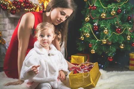 Cute baby and mum decorating a Christmas tree. Red balls.の写真素材