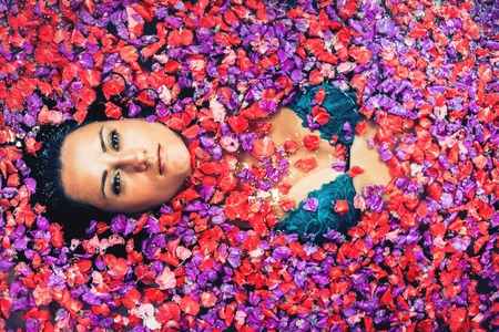 Woman relaxing bath with tropical flowers outdoor at luxury hotelの写真素材