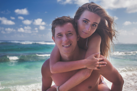Portrait of happy couple taveling at Bali, walking at beachの写真素材