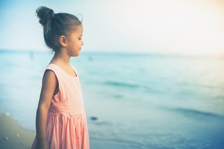 Beautiful little girl at the beach. Sunblock cream for children.の写真素材