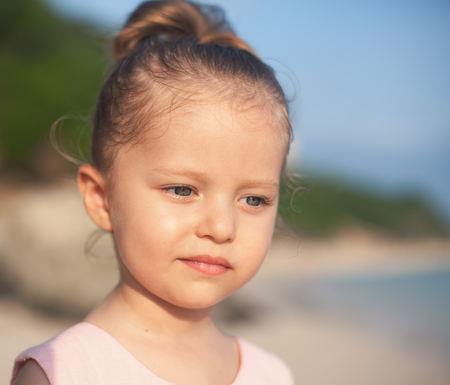 Beautiful little girl at the beach. Sunblock cream for children.の写真素材