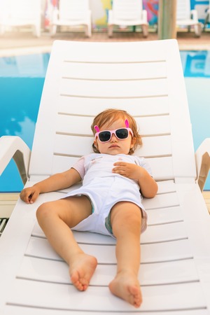 Cute baby relaxing at sunbed near pool at hawaii, hotelの写真素材