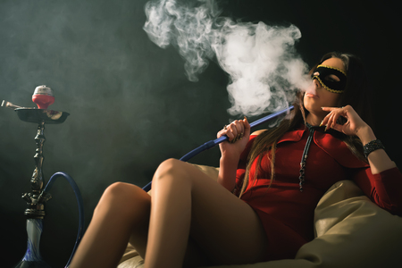 Young, beautiful girl smoke a hookah at clubの写真素材