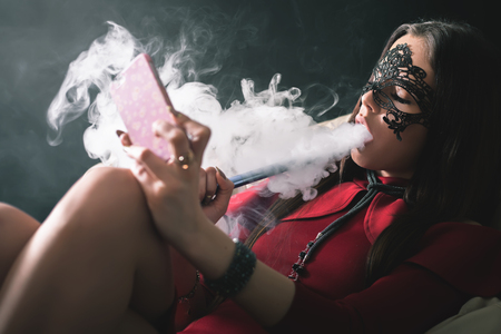 Young, beautiful girl with carnival mask smoke a hookah