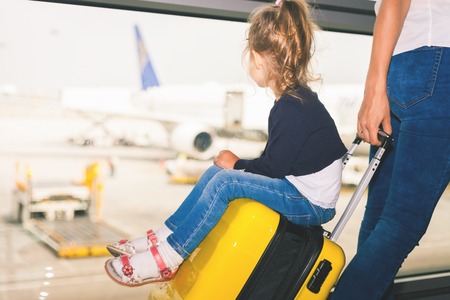 Mom carries your luggage with happy baby at airport terminal.の写真素材