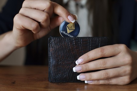 Successfully woman put Ethereum con into wallet. Crypto coin saving.の写真素材