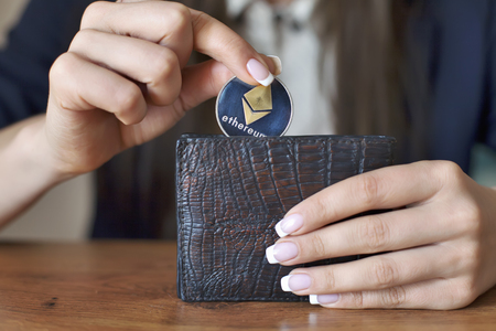 Successfully woman put Ethereum con into wallet. Crypto coin saving.の写真素材