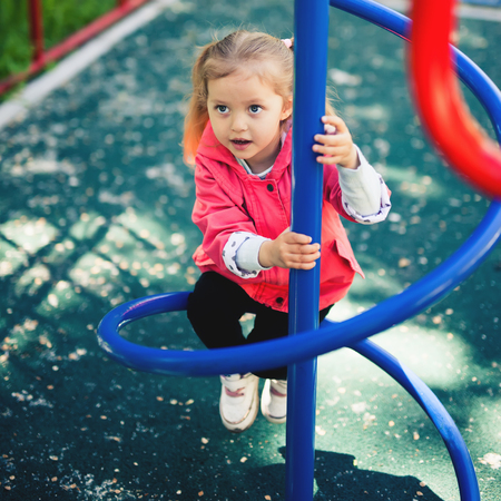 Climbing little girl at playground. Playground outdoor in summer timeの写真素材