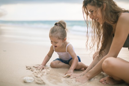 Childrens Day. Mom and baby playing near beach.の写真素材