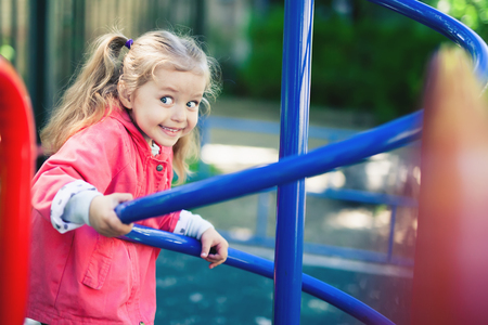 Climbing little girl at playground. Playground outdoor in summer timeの写真素材