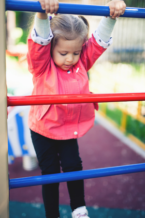Climbing little girl at playground. Playground outdoor in summer timeの写真素材