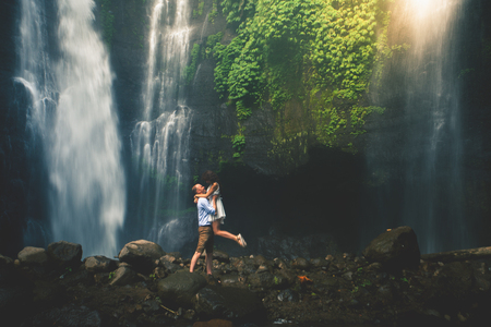 Amazing romantic view of happy couple near beautiful grand waterfallの写真素材