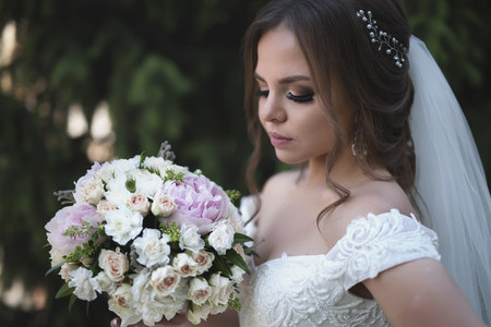 Portrait of Bride holds wedding bouquet at green summer background.の写真素材