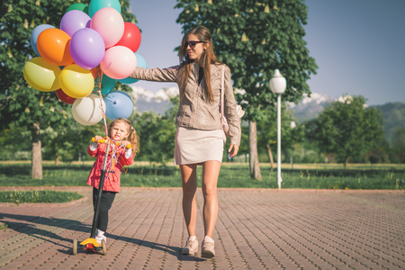 Happy child and mom with balloons walk outdoor.の写真素材