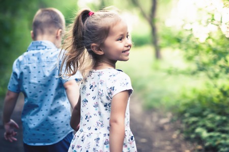 Happy kids walking outdoor at park hold their hands.の写真素材