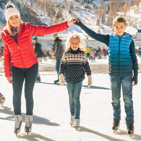 Happy family outdoor ice skating at rink. Winter activitiesの写真素材