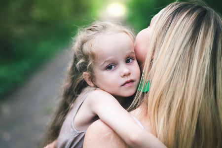 Beautiful young woman and her charming little daughter are huggingの写真素材
