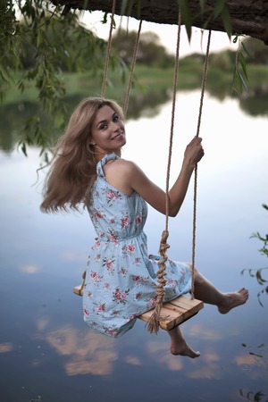 Sexy woman swinging on the swing outdoor. Hair free legsの写真素材