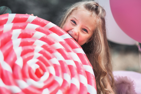 Funny little girl eats big lollipop at her partyの写真素材