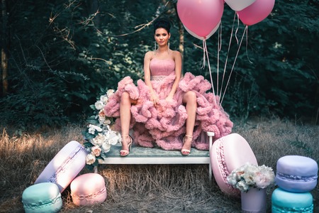 Fashion sexy woman dressed in pink stunning dress surrounded of French Macaronsの写真素材