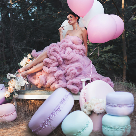 Fashion sexy woman dressed in pink stunning dress surrounded of French Macaronsの写真素材
