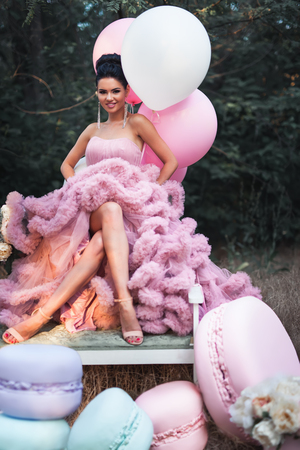 Fashion sexy woman dressed in pink stunning dress surrounded of French Macaronsの写真素材