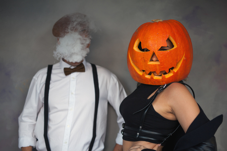 Unusual couple at Halloween party, Woman with pumpkin on headの写真素材