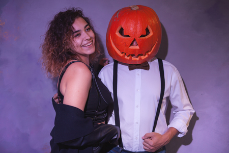 Unusual couple at Halloween party, Woman with pumpkin on headの写真素材