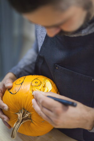 Man carves a pumpkin to decorate the Halloweenの写真素材