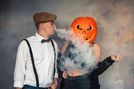 Unusual couple at Halloween party, Woman with pumpkin on headの写真素材