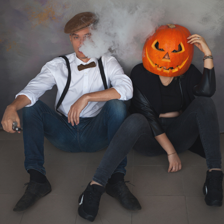 Unusual couple at Halloween party, Woman with pumpkin on headの写真素材