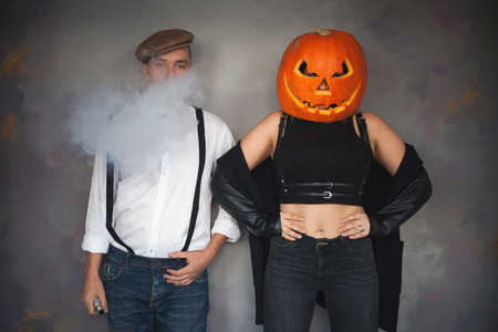 Unusual couple at Halloween party, Woman with pumpkin on headの写真素材
