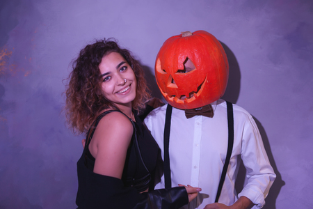Unusual couple at Halloween party, Woman with pumpkin on headの写真素材