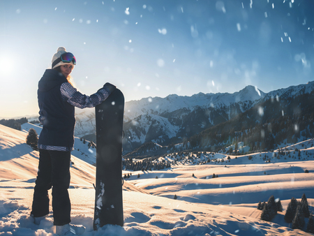 Adventure to winter sport. Snowboarder girl on background high mountainの写真素材