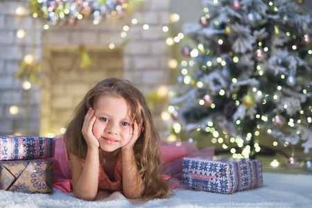Happy child girl lies at her decorated kids room on Christmas nightの写真素材
