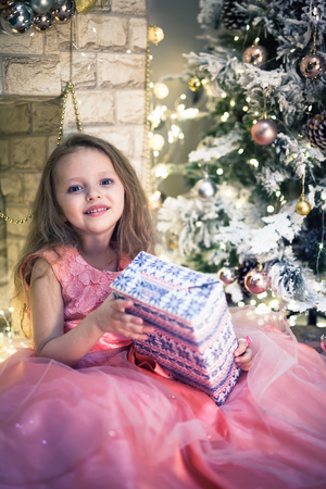 Happy child girl unpacks her present on Christmas night.の写真素材
