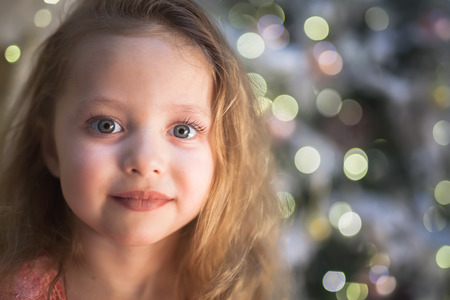 Little girl at Christmas with Christmas tree at backgroundの写真素材