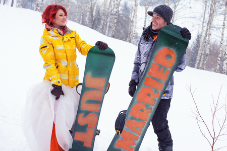 Wedding snowboarders couple just married at mountain winterの写真素材