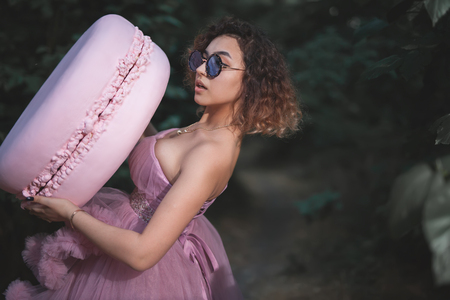 Unusual hipster woman holds a big French Macaron at her partyの写真素材