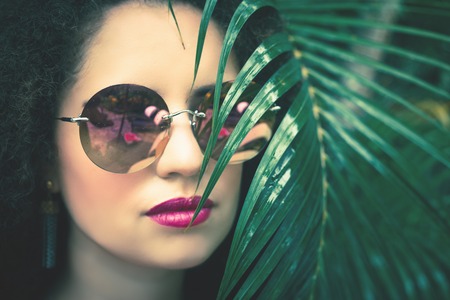 Beautiful woman with green palm leaves at her faceの写真素材