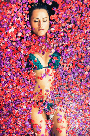 Woman relaxing bath with tropical flowers outdoor at luxury hotelの写真素材