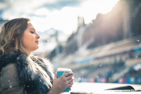 Beautiful girl resting and drinking coffee after ice skatingの写真素材