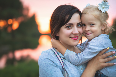 Beautiful young woman and her charming little daughter are huggingの写真素材