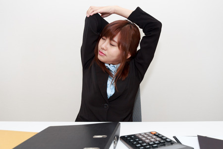 Businesswoman stretching herself or exercise while working at officeの写真素材
