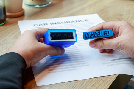 Businesswoman holding approved and cancelled rubber stamp to make a decision on car insurance.